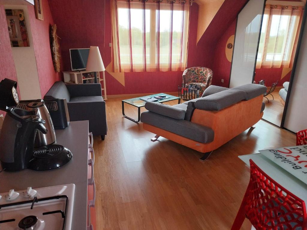 - un salon avec des murs rouges, un canapé et des chaises dans l'établissement Blandine & Christian, à Saint-Judoce