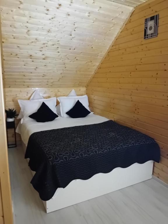 ein Schlafzimmer mit einem Bett in einer Holzwand in der Unterkunft Căsuța Piatra Craiului in Zărneşti