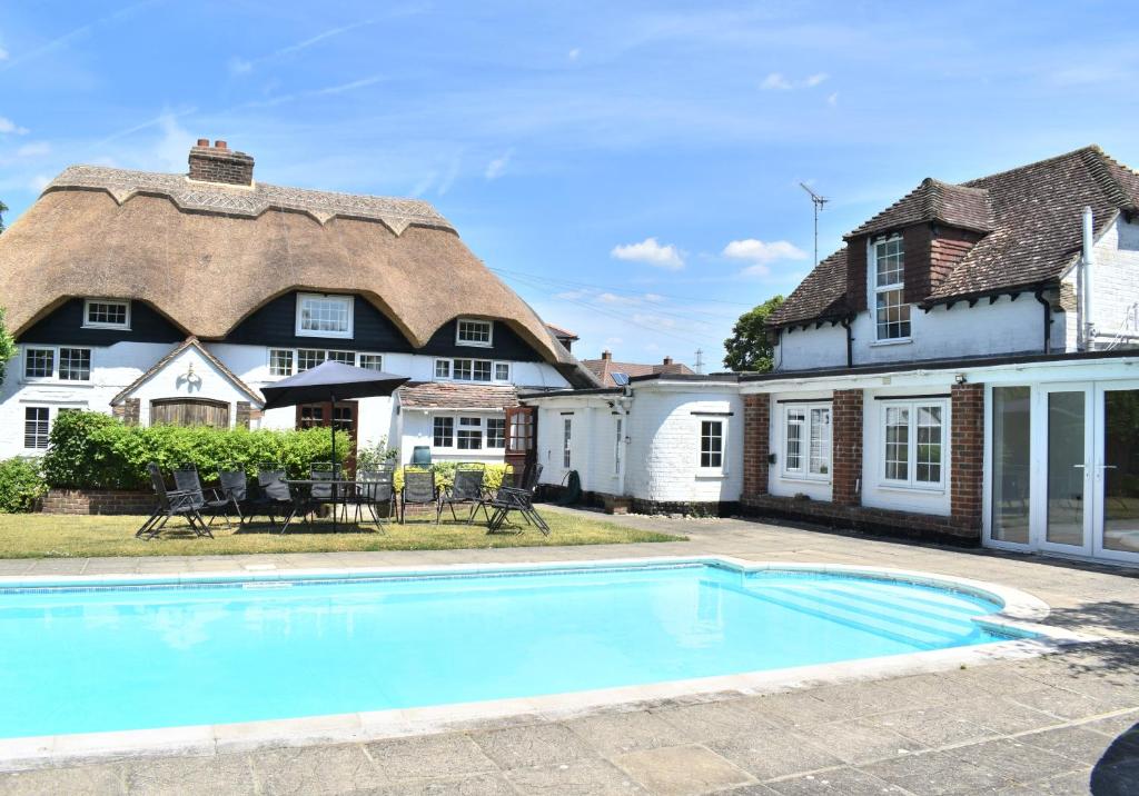 a large house with a swimming pool in front of it at Beautiful Thatched Cottage with heated outdoor pool, Great for families & Dog Friendly! in Bosham