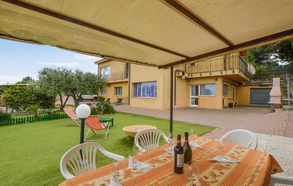 un patio con tavolo, sedie e bottiglie di vino di 3 Bedroom Amazing Apartment In Imperia a Imperia