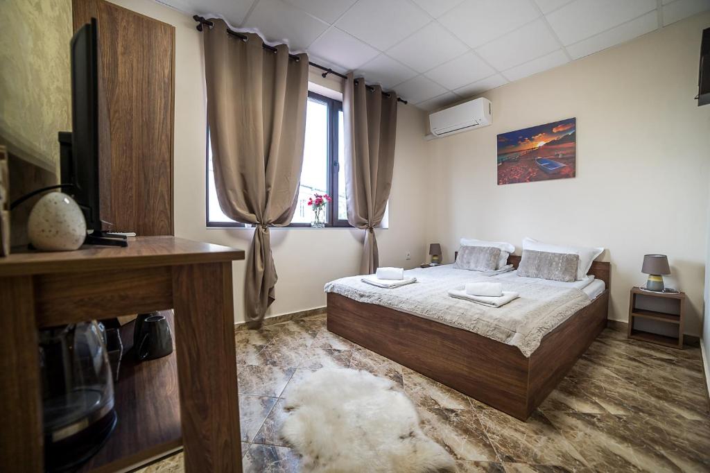 a bedroom with a bed and a television in it at Къща за гости Алекс in Karlovo