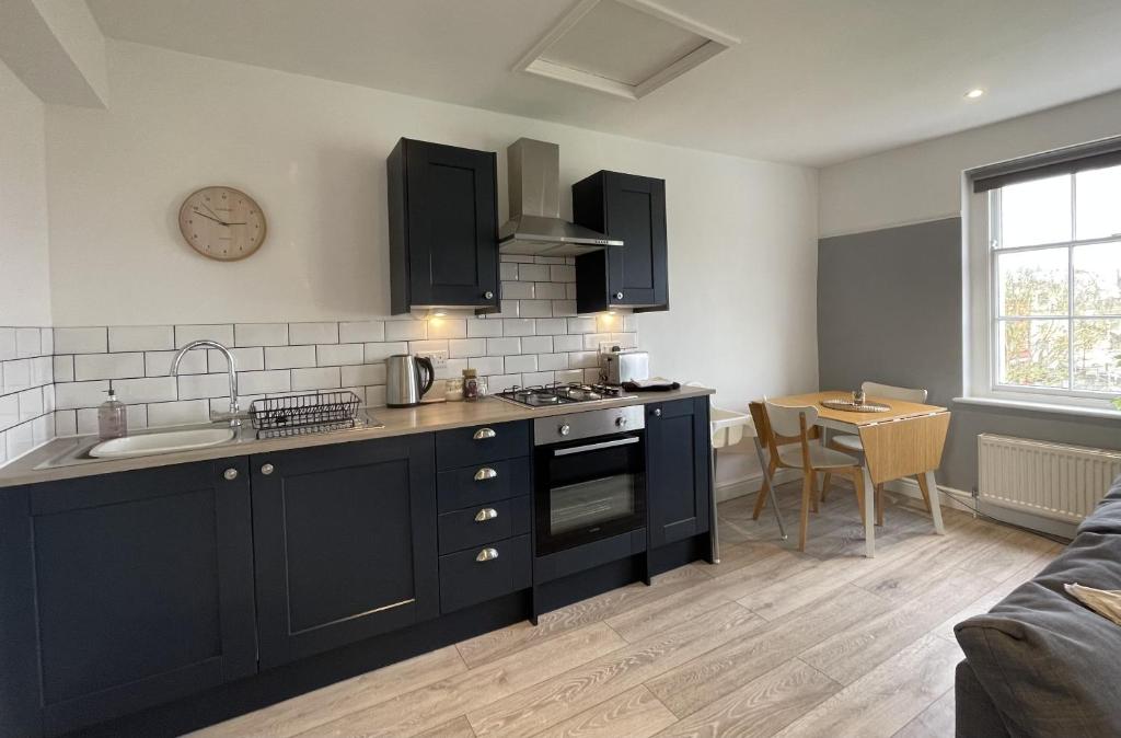 a kitchen with black cabinets and a sink and a table at Apartment 4 St Georges in Cheltenham