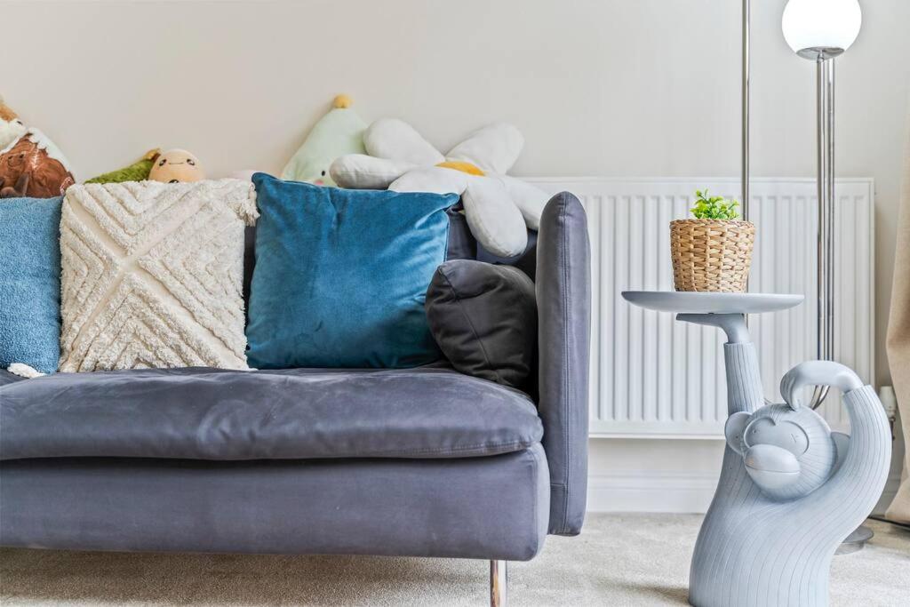 um sofá azul com almofadas na sala de estar em Large 2-Bed House next to Warwick Uni 2x Parking em Canley