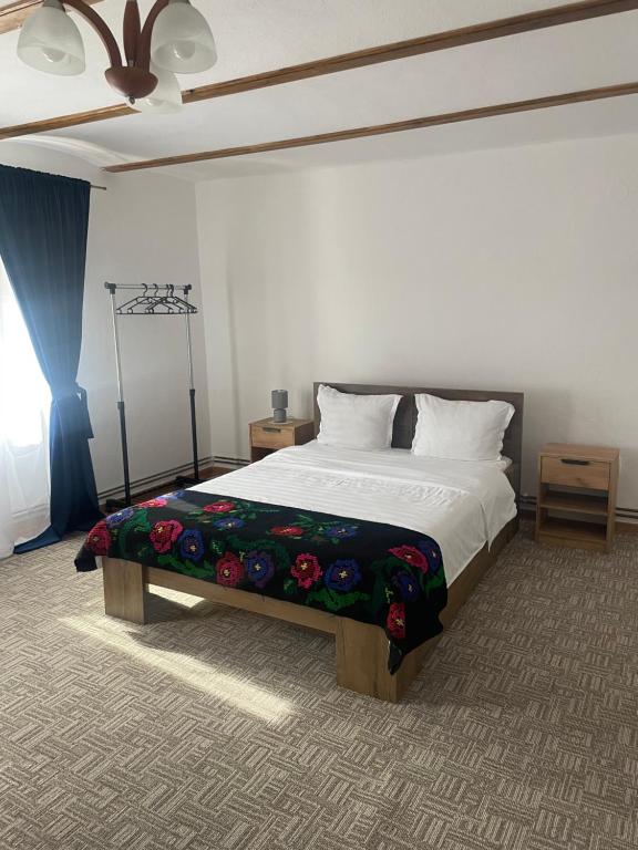 een slaapkamer met een groot bed met bloemen erop bij Casa de Vacanta FAMILY & FRIENDS in Criţ