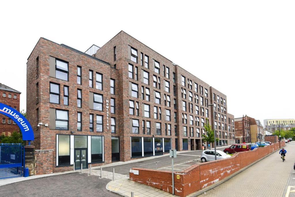 a large brick building with cars parked in front of it at Conveniently Situated Ensuite Rooms and Studios at Newcastle 1, Near Main Universities in Newcastle upon Tyne
