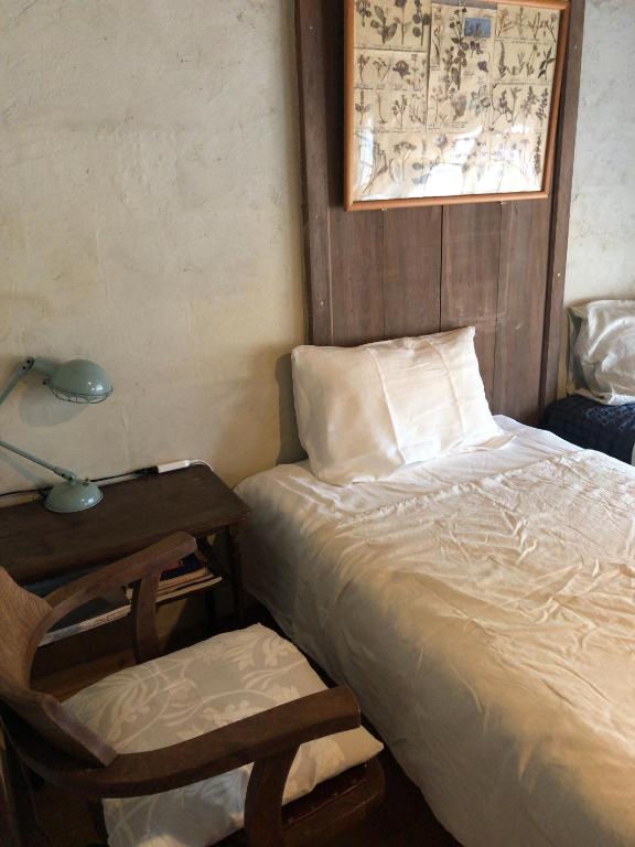 a bedroom with a bed and a lamp and a chair at Travelers House おーさんてぃん青空舎 in Taketomi