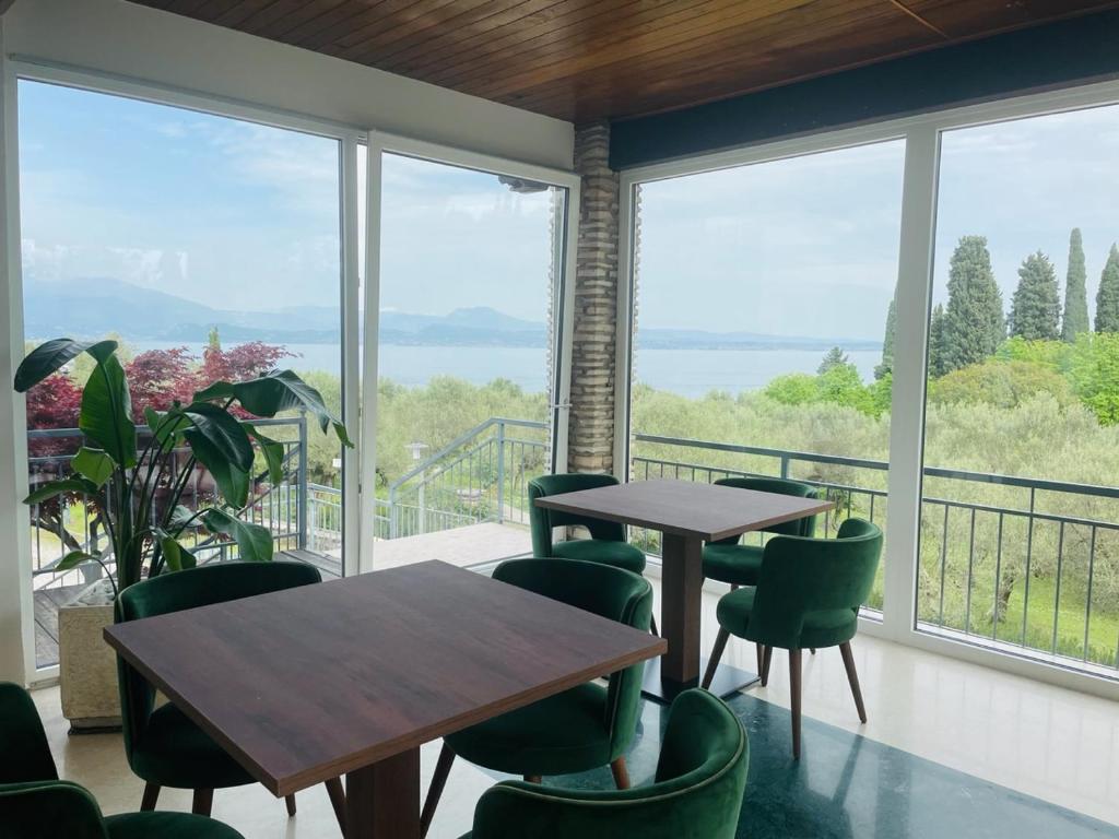 two tables and chairs in a room with windows at Hotel Mon Repos in Sirmione