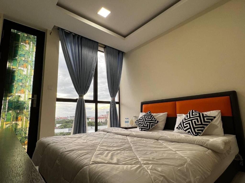 a bedroom with a bed and a large window at Condo Orkide in Phnom Penh