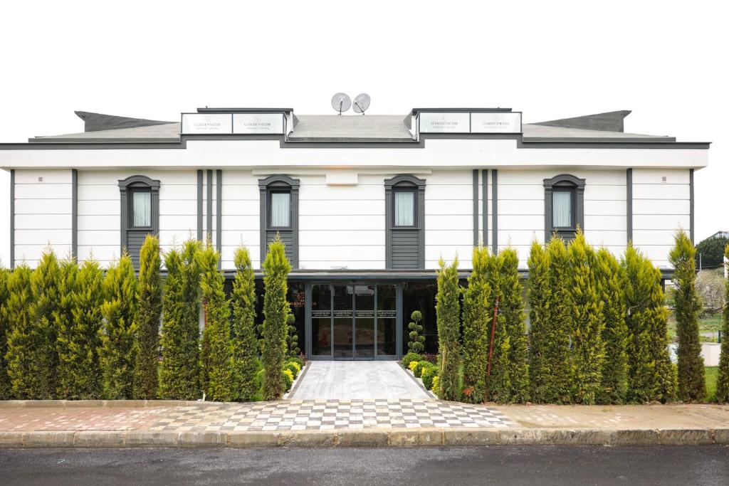 un edificio blanco con una puerta y arbustos en Gardenmode Airport Hotel, en Taşoluk