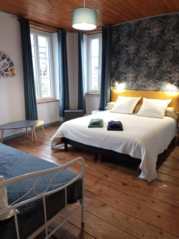 a bedroom with a large bed and two windows at La Lendeline in Saint-Sauveur-Lendelin