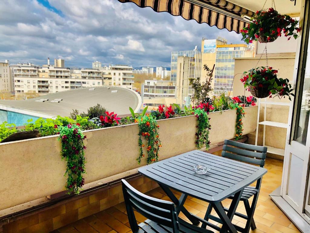 a table and chairs on a balcony with flowers at Chambre Privée en colocation dans un appartement Vaulx en Velin Centre in Vaulx-en-Velin