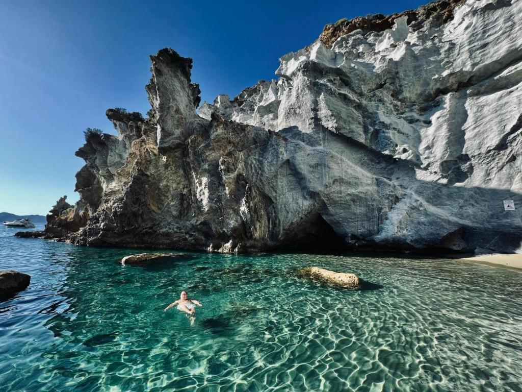 un uomo che nuota nell'acqua vicino a una spiaggia rocciosa di Casa Acqua Marina Le Forna a Ponza