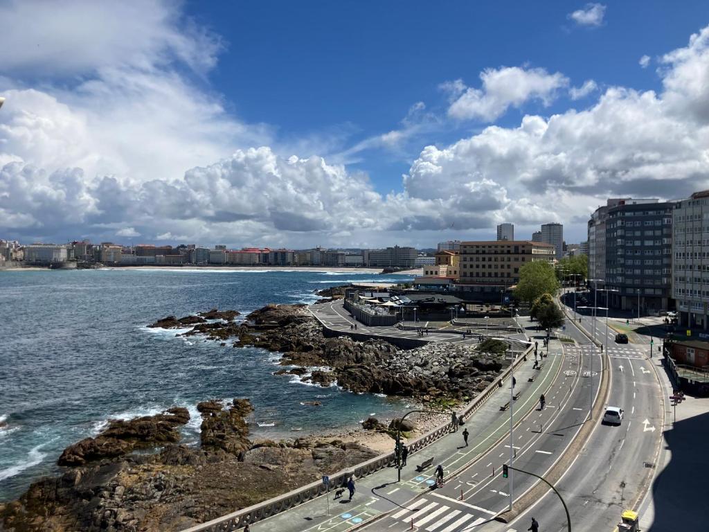a road next to a body of water with buildings at Riazor San Roque de Afuera in A Coruña