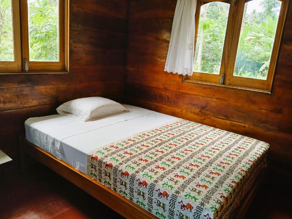 uma pequena cama num quarto com duas janelas em Big Mama's Little House Casa da Mãe Grande em Porto Alegre