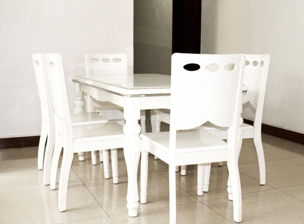 Una mesa de comedor blanca y cuatro sillas blancas. en Waridi Apartment, en Dar es Salaam
