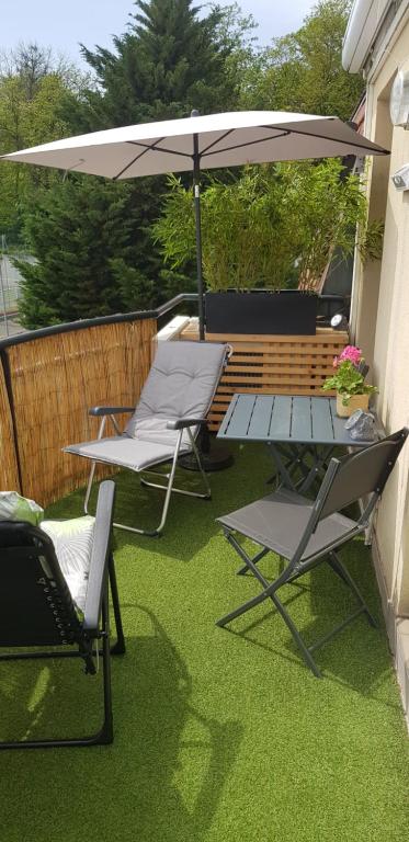 eine Terrasse mit 2 Stühlen, einem Tisch und einem Sonnenschirm in der Unterkunft Green Field Lodge in Lingolsheim