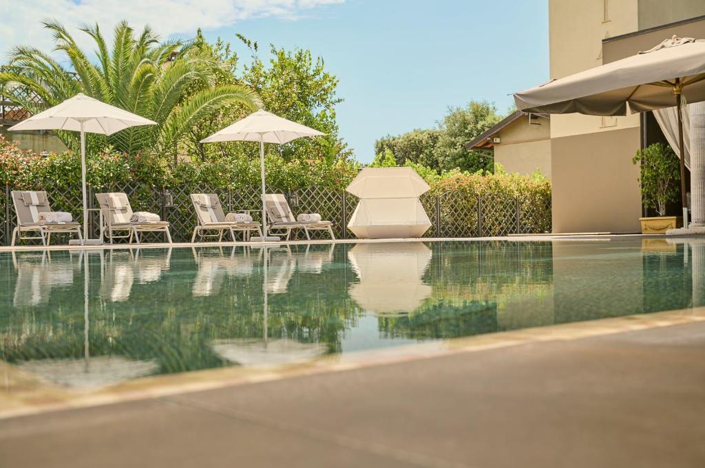 a swimming pool with two umbrellas and chairs and a pool at Grand Hotel Imperiale in Forte dei Marmi