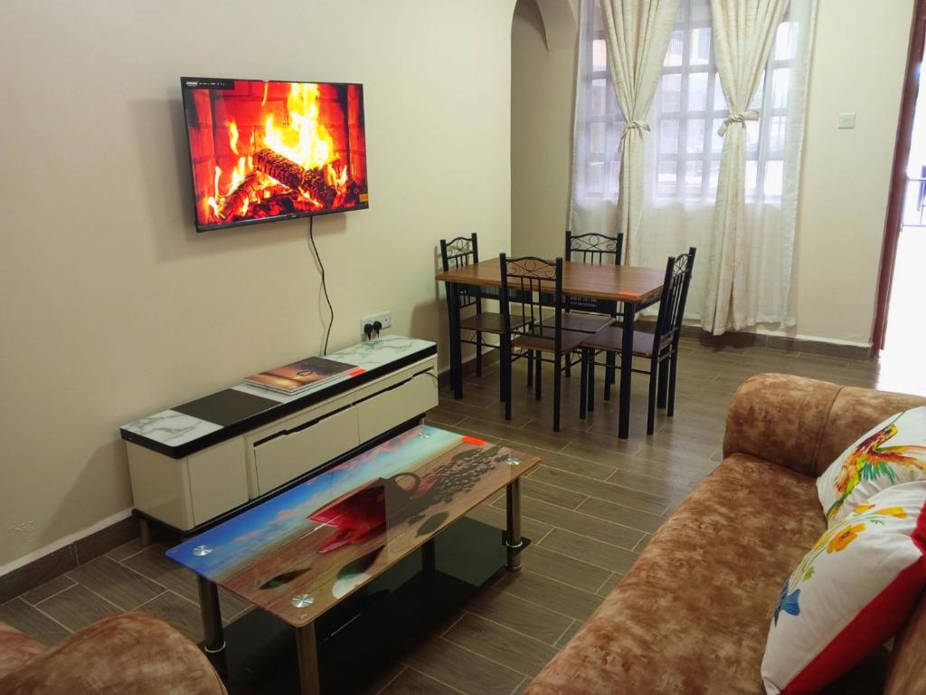 a living room with a couch and a fire on the wall at Greenview apartments nanyuki in Nanyuki