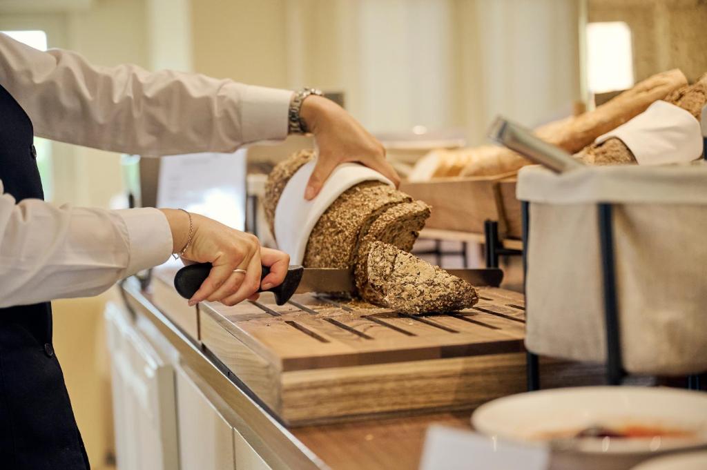 a person cutting bread with a knife on a counter at Grand Hotel Imperiale in Forte dei Marmi