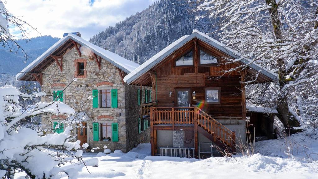 uma cabana de madeira na neve nas montanhas em The Stone House - 10 Bed Chalet near Morzine em Saint-Jean-dʼAulps