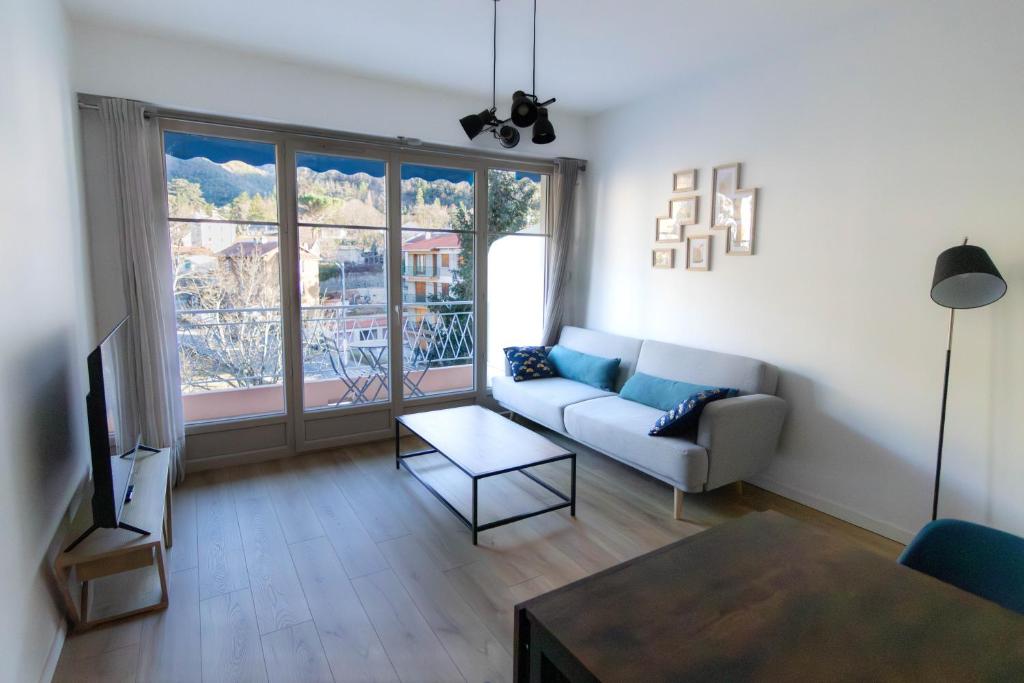 un salon avec un canapé et une grande fenêtre dans l'établissement Les Cimes En Vue, 3 étoiles - Résidence Le Palais, à Vernet-les-Bains