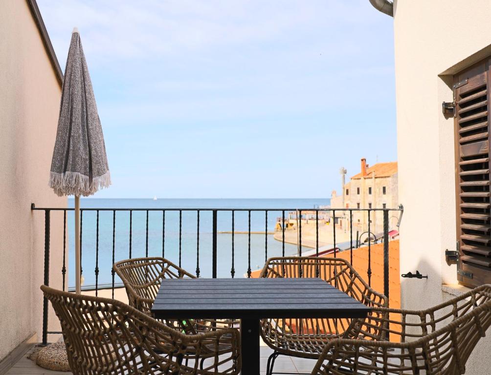 a table and chairs on a balcony with a view of the beach at Apartments Dante in Umag
