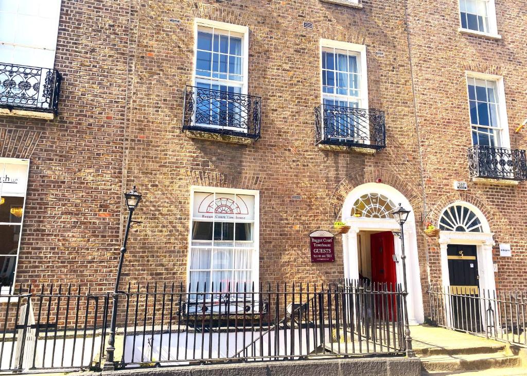a brick building with a red door and windows at Baggot Court Townhouse in Dublin