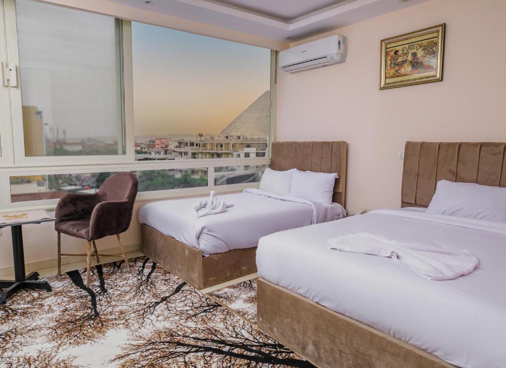 Pokój hotelowy z 2 łóżkami, biurkiem i oknem w obiekcie Mak Pyramids View w Kairze