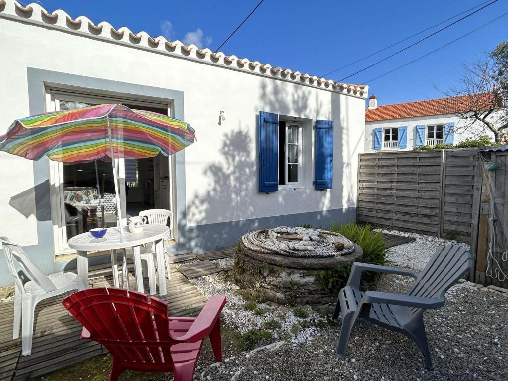 un patio avec une table, des chaises et un parasol dans l'établissement Petite maison neuve à 250m de la plage avec jardin clos, terrasse et parking - L'Épine - FR-1-224B-190, à LʼÉpine