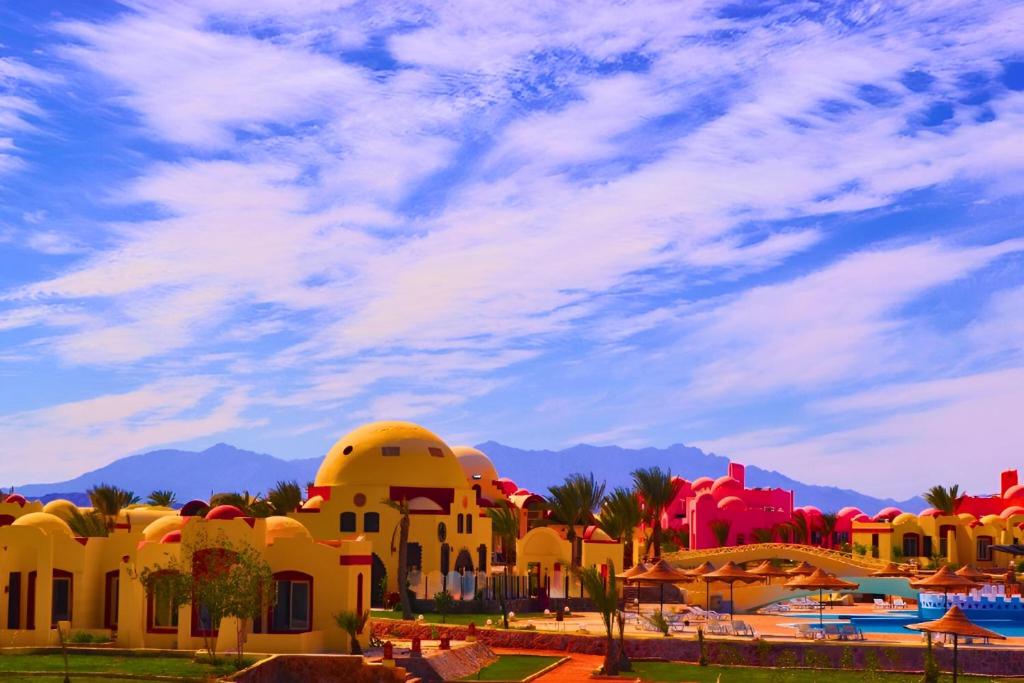 Abū Ghuşūn的住宿－Hostmark Zabargad Beach Resort，享有拥有建筑和棕榈树的度假村的景色