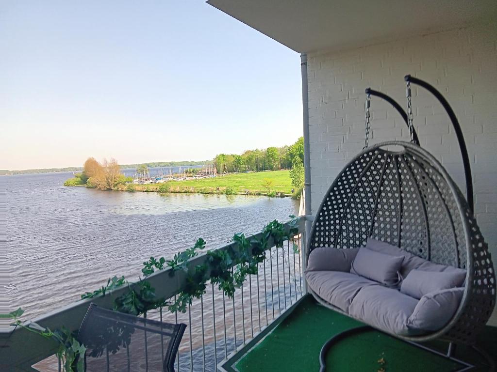 um alpendre com um baloiço e vista para um rio em Ferienwohnung mit Meerblick in Bad Zwischenahn em Bad Zwischenahn