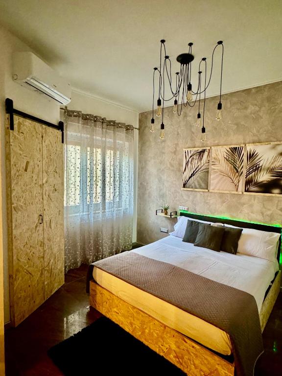 a bedroom with a large bed and a chandelier at Del Regno Holiday House in Pompei
