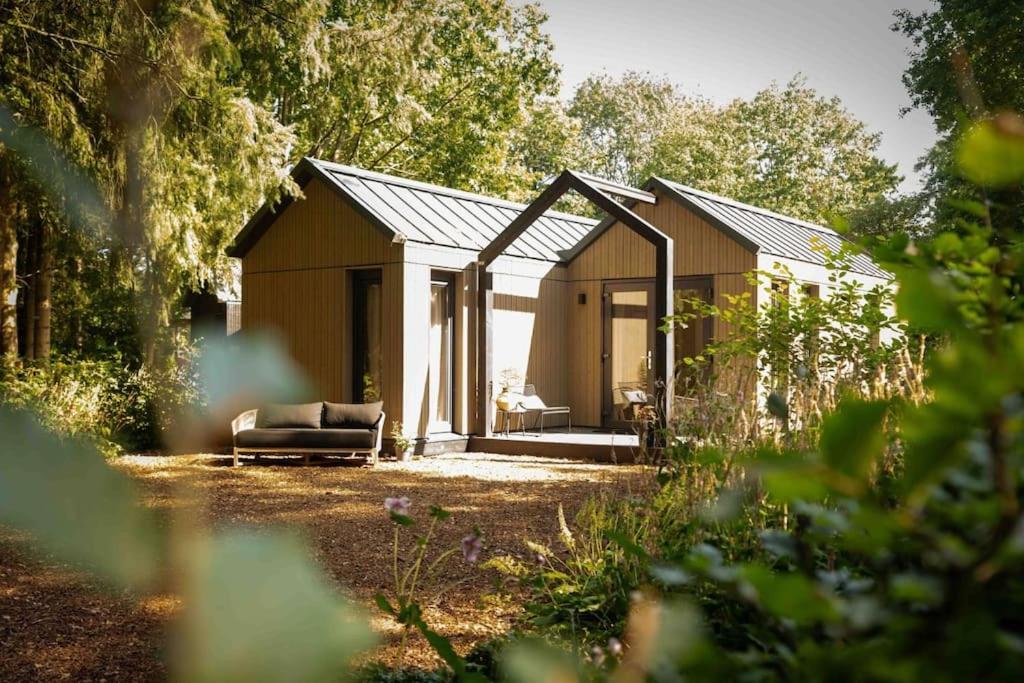 a house with a couch sitting outside of it at Sød I Tiny house in Epe