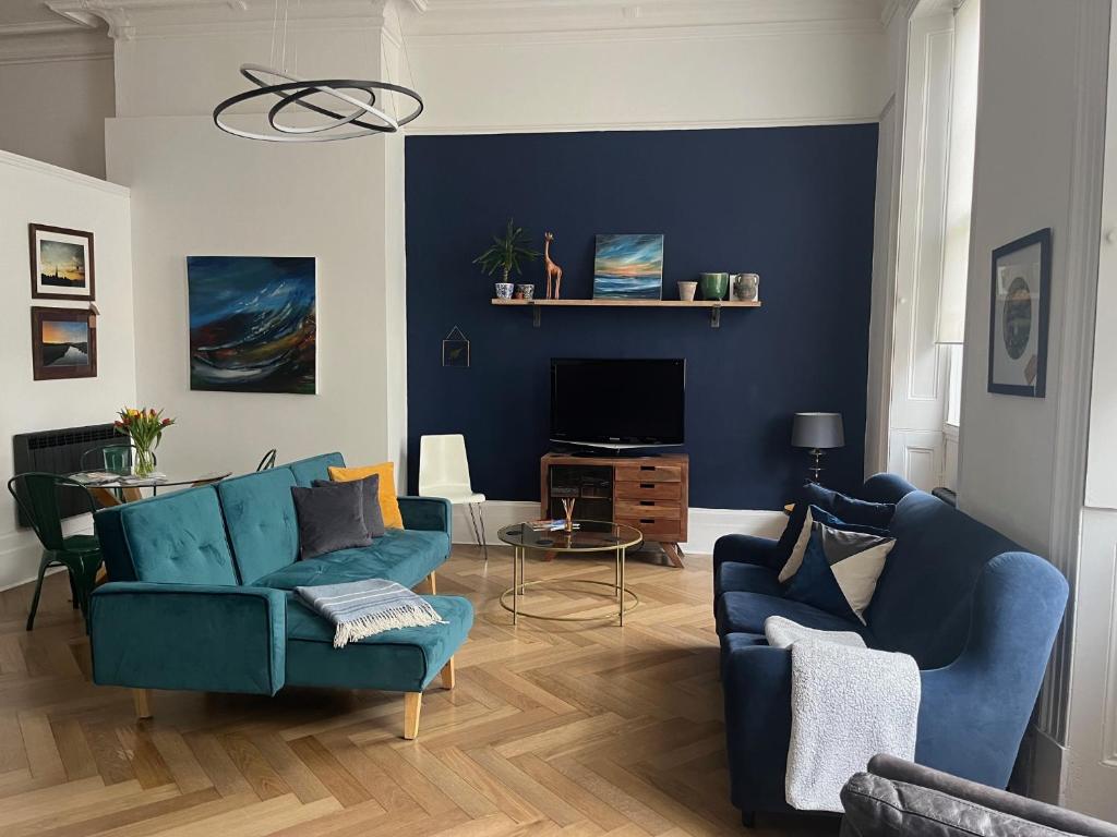 a living room with two blue couches and a tv at 6 Wye Valley Chambers, Ross-on-Wye in Ross on Wye