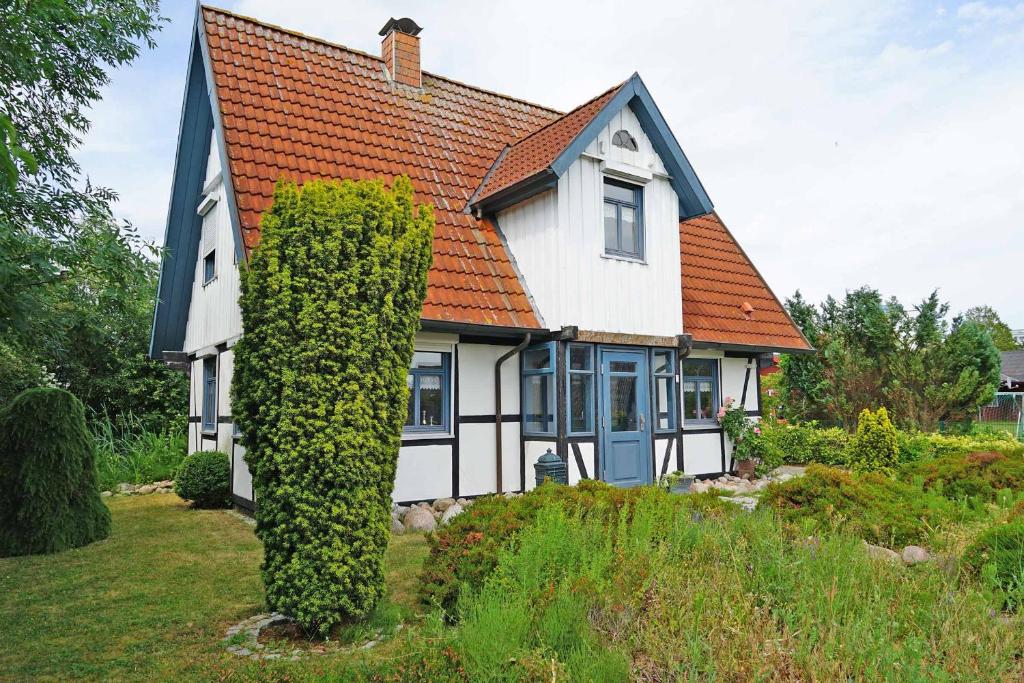 een huis met een oranje dak en een groene heg bij Ferienhaus mit viel Platz in Strandnaehe in Damp