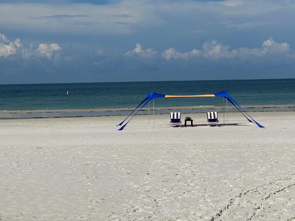 two chairs and a blue canopy on a beach at Private condo just steps to St Pete Beach in St Pete Beach