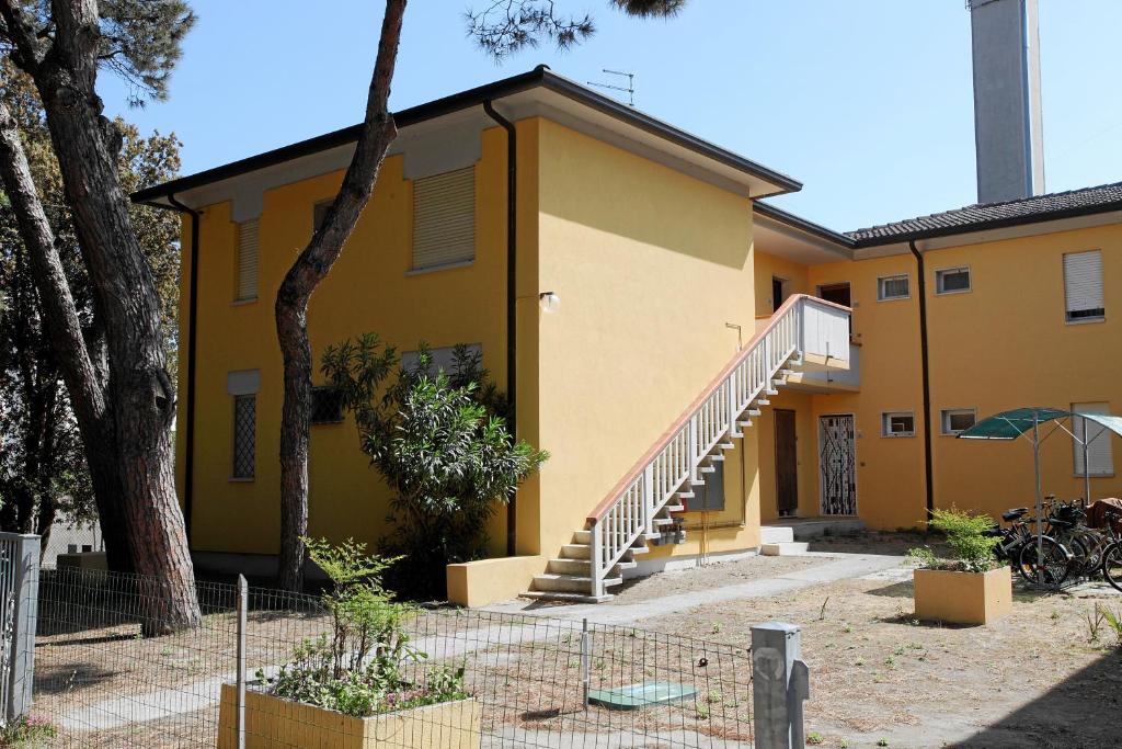 une maison jaune avec un escalier devant elle dans l'établissement Villa Medea, à Rosolina Mare