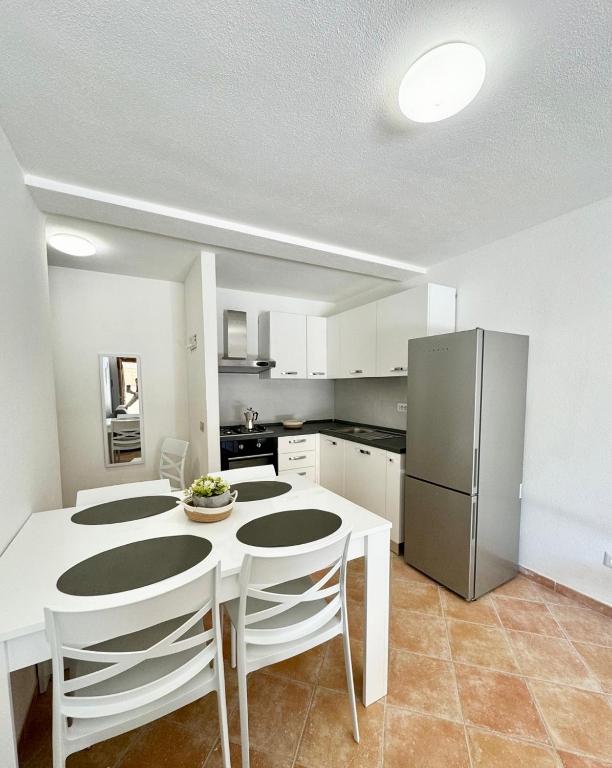 a kitchen with a white table and a refrigerator at Le case in collina - San Teodoro in Lu Lioni