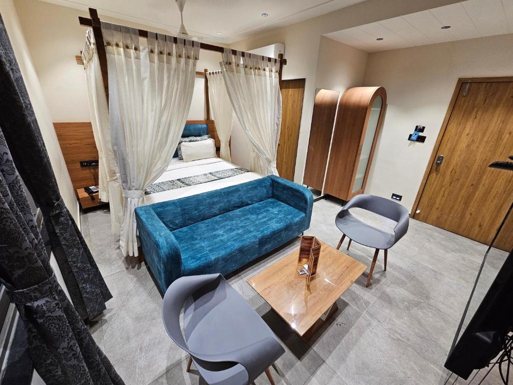 1 dormitorio con 1 cama y 1 sofá azul en Hotel Nova Palm, en Rajkot