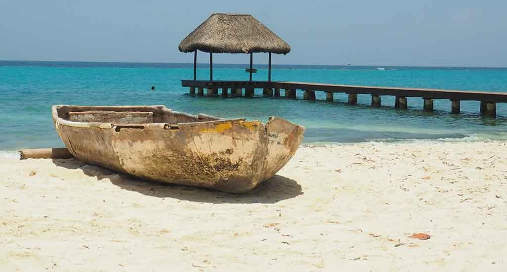 un viejo barco sentado en la playa con un muelle en Hotel Las Casitas De Mar Adentro, en Isla Grande