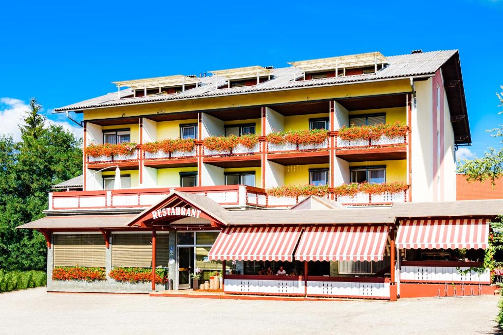 un bâtiment d'hôtel avec des fleurs sur les balcons dans l'établissement Gasthof Menüwirt, à Sankt Kanzian