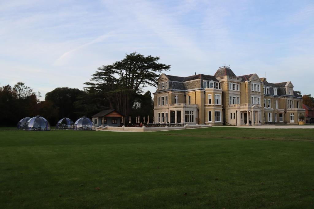 una casa grande con un gran campo de césped enfrente en The Mansion en Southampton