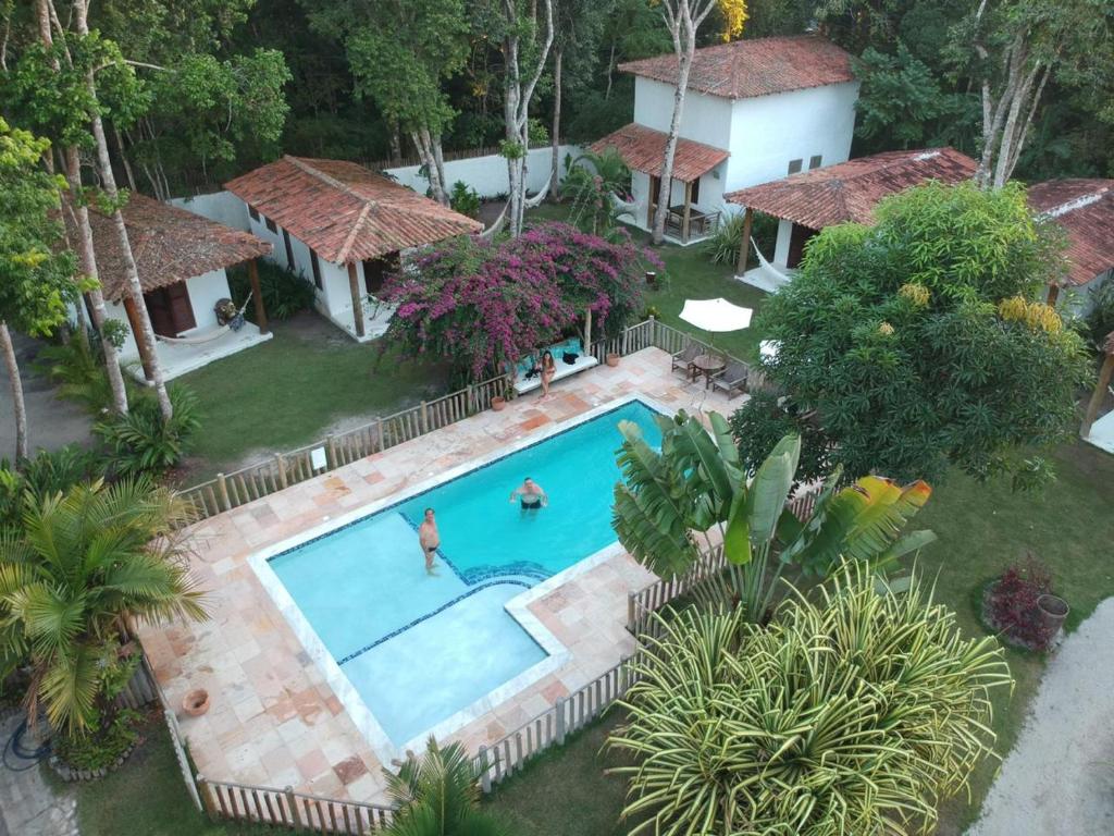 una vista aérea de una piscina con dos personas en ella en Cheiro Nativo - Chalés & Pousada, en Trancoso
