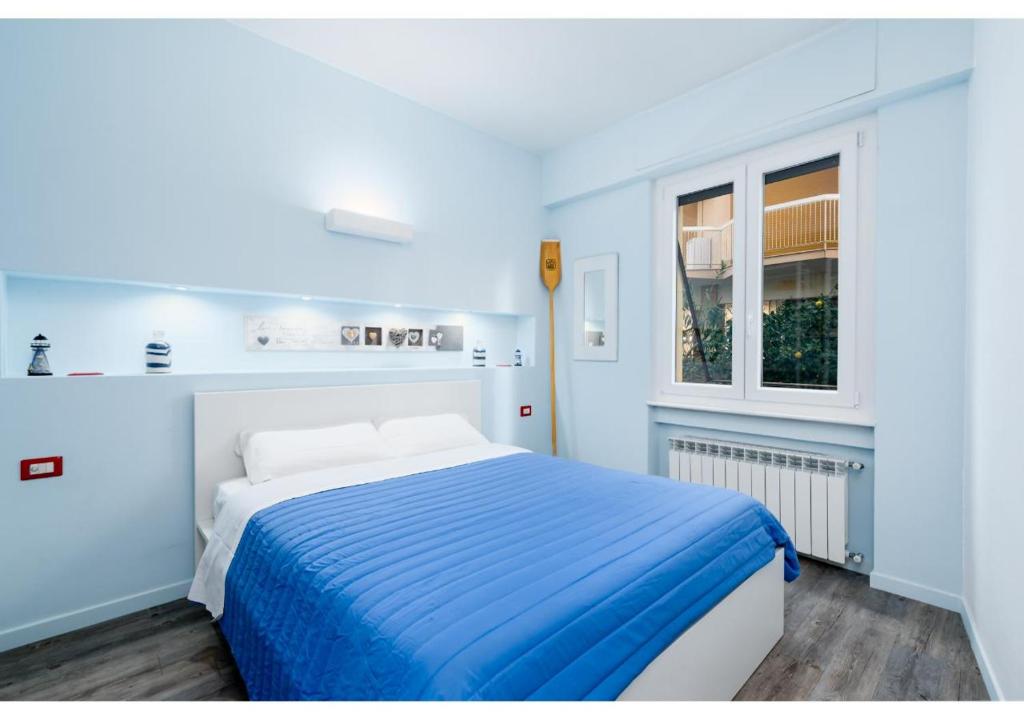 niebieska sypialnia z łóżkiem i oknem w obiekcie Diamante Sea Apartment w mieście Varigotti