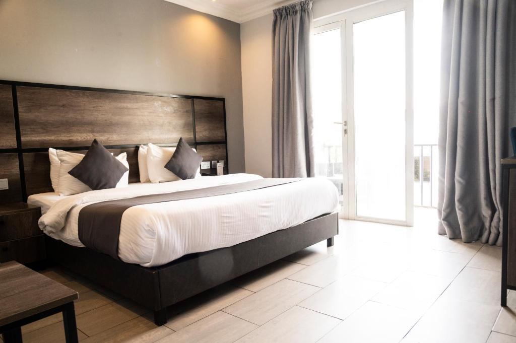 Schlafzimmer mit einem großen Bett mit einem Kopfteil aus Holz in der Unterkunft The Blowfish Hotel in Lagos