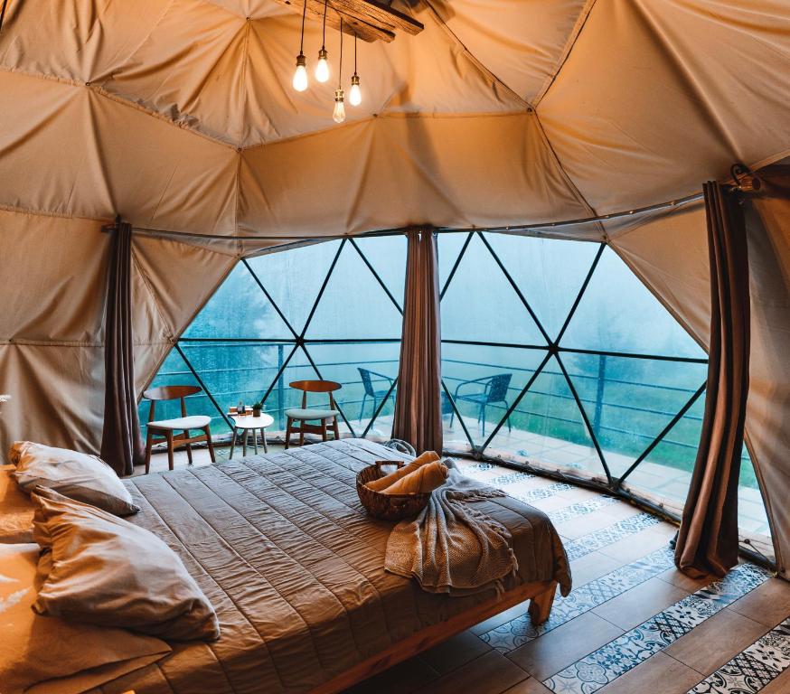 a bedroom in a tent with a large window at Green Noise Glamping in Fraijanes