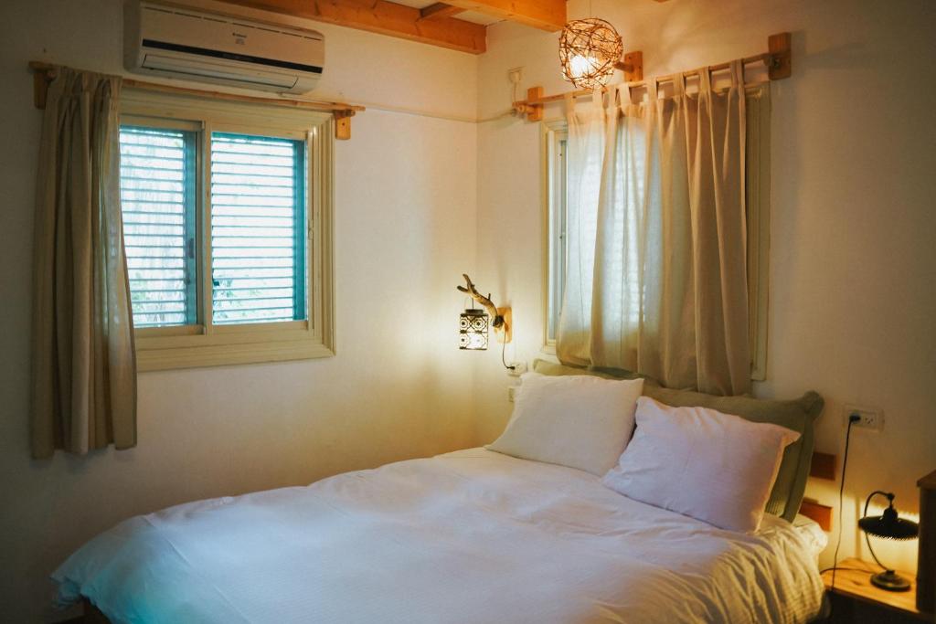 een slaapkamer met een wit bed en een raam bij Blue House In The Woods- Amirim in Amirim