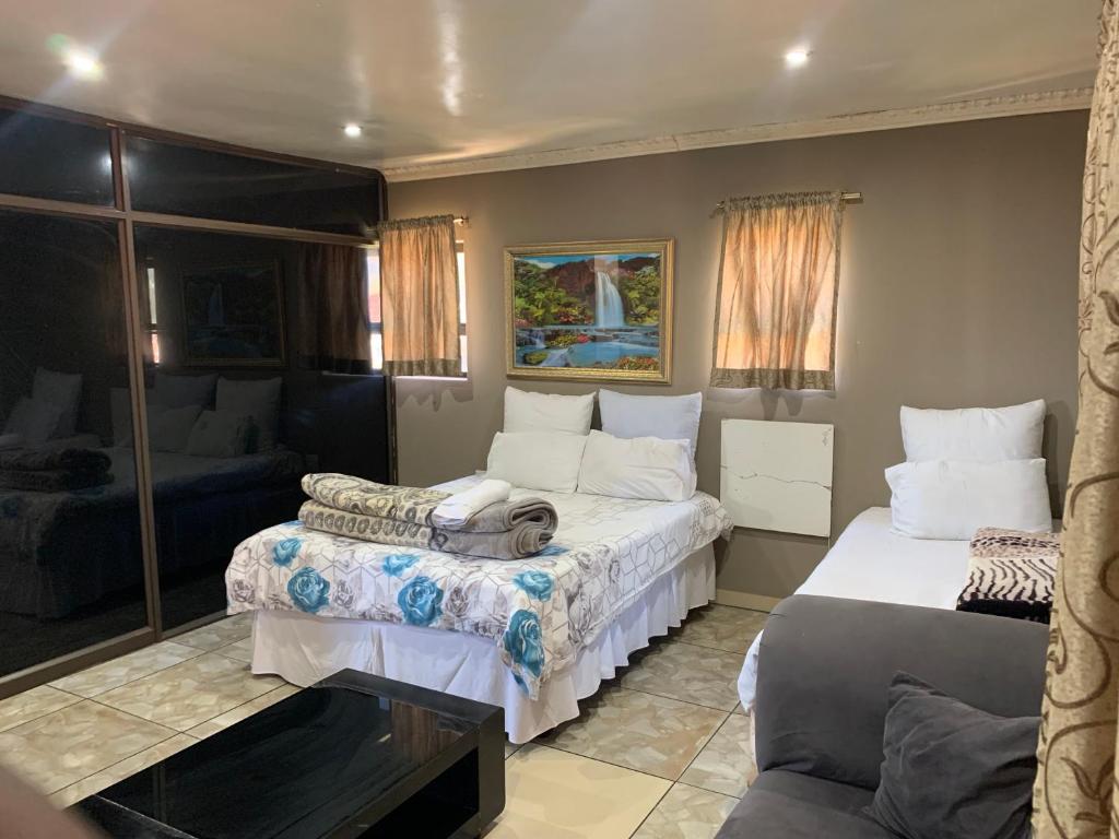 Johannesburg的住宿－M & J HOTELS，一间带两张床和一张沙发的卧室