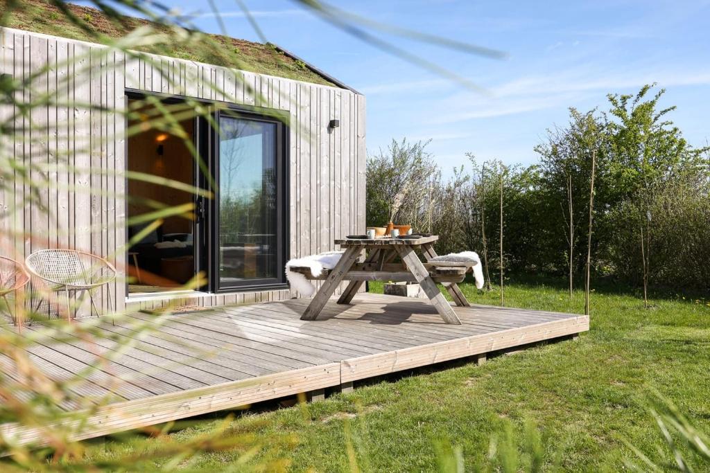 ヴェストカペレにあるHello Zeeland - Tiny House Zeeuwse Liefde 2の木製デッキ(家の上にピクニックテーブル付)