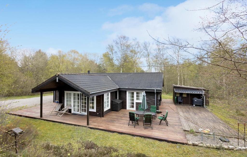 une petite cabine avec une terrasse dans les bois dans l'établissement Nice Home In Sby With Kitchen, à Sæby